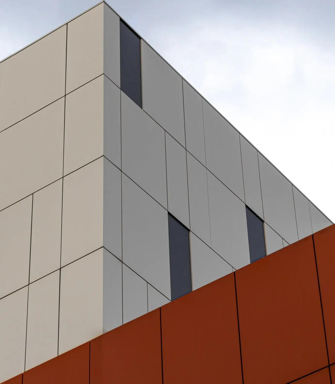 Low-angle perspective of a modern white and orange building under the bright sky